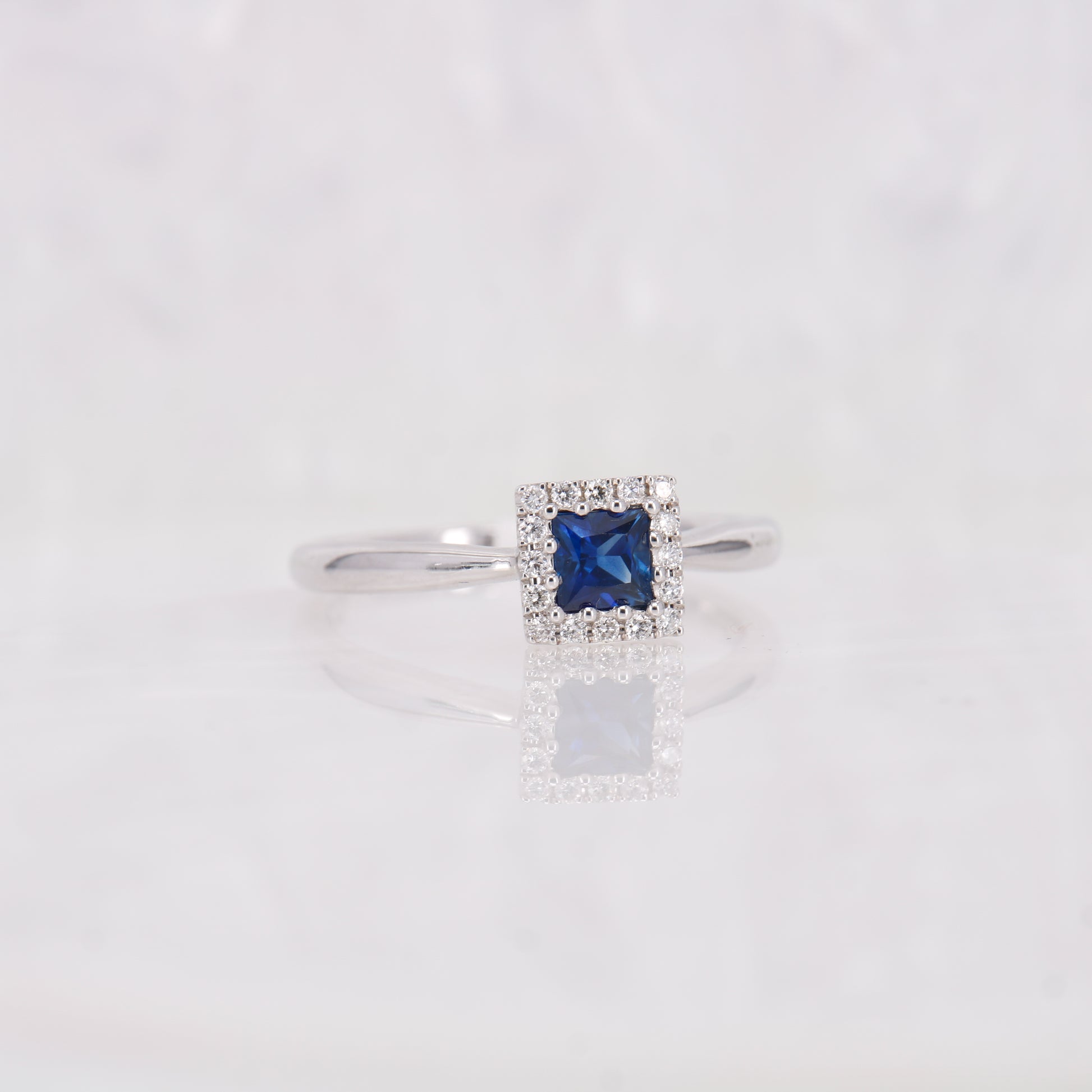 Sapphire and Diamond ring. Featuring a 0.45ct princess cut sapphire surrounded by a sparkling 0.10ct diamond halo.