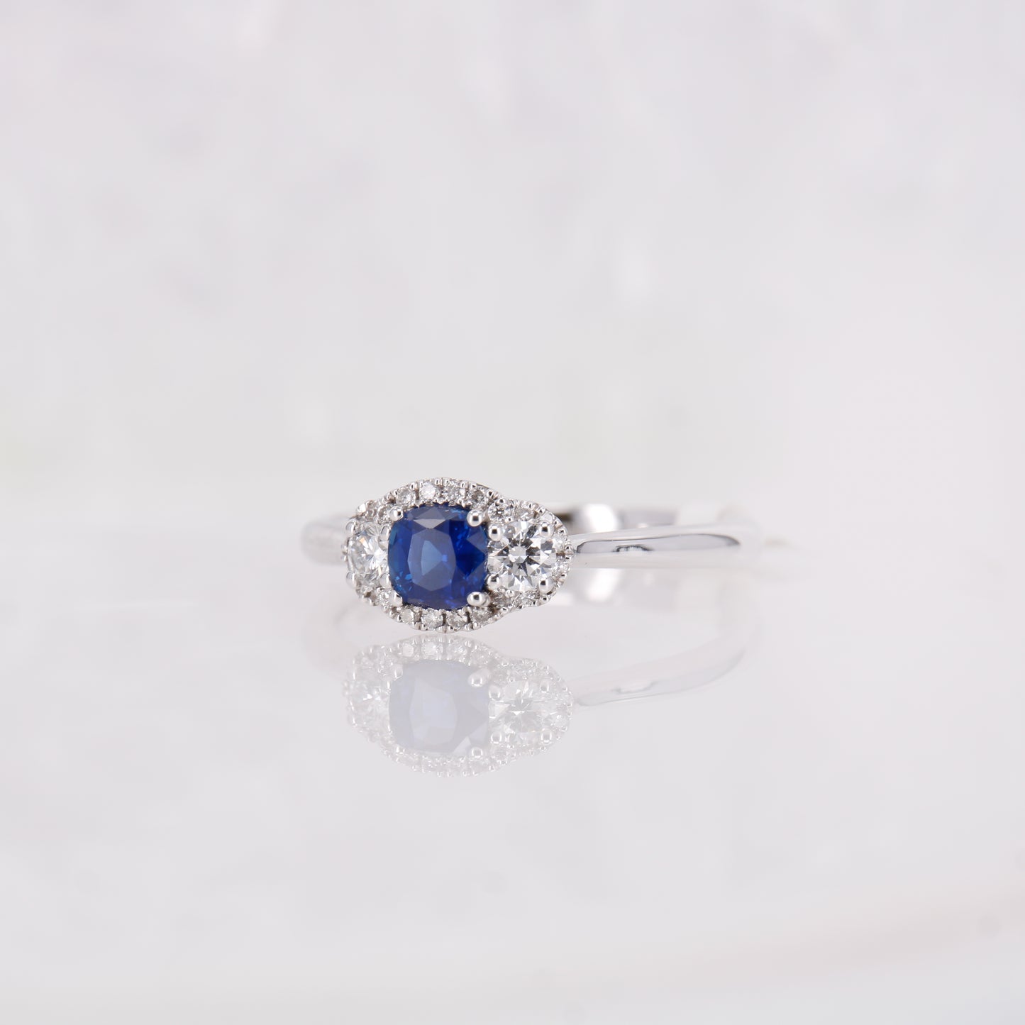 18CT White Gold Sapphire and Diamond three stone ring with a halo of diamonds surrounding. 