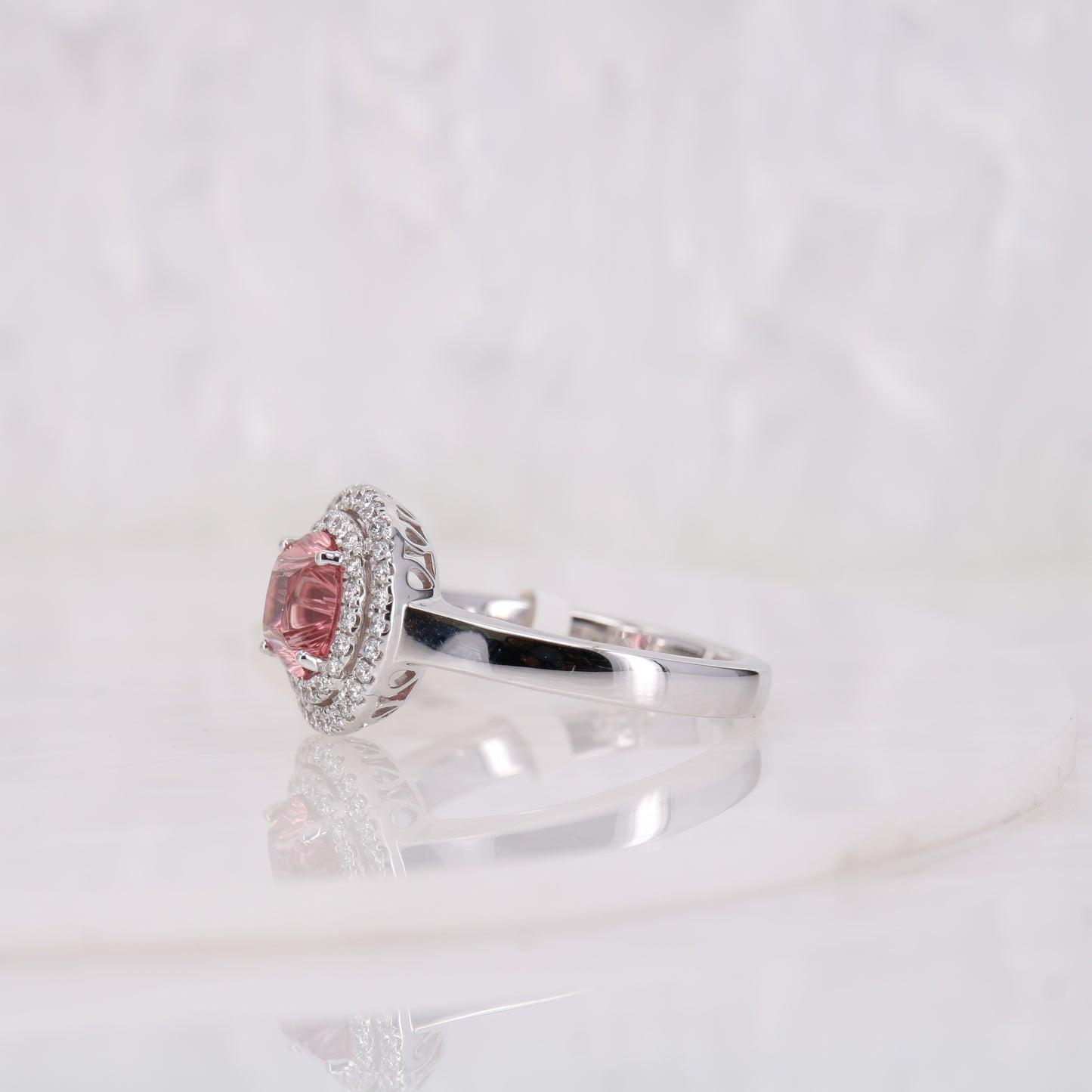 Pink Tourmaline and Diamond ring. Featuring a striking faceted 1.49ct round brilliant cut carved pink tourmaline and complimented by a double halo of diamonds.