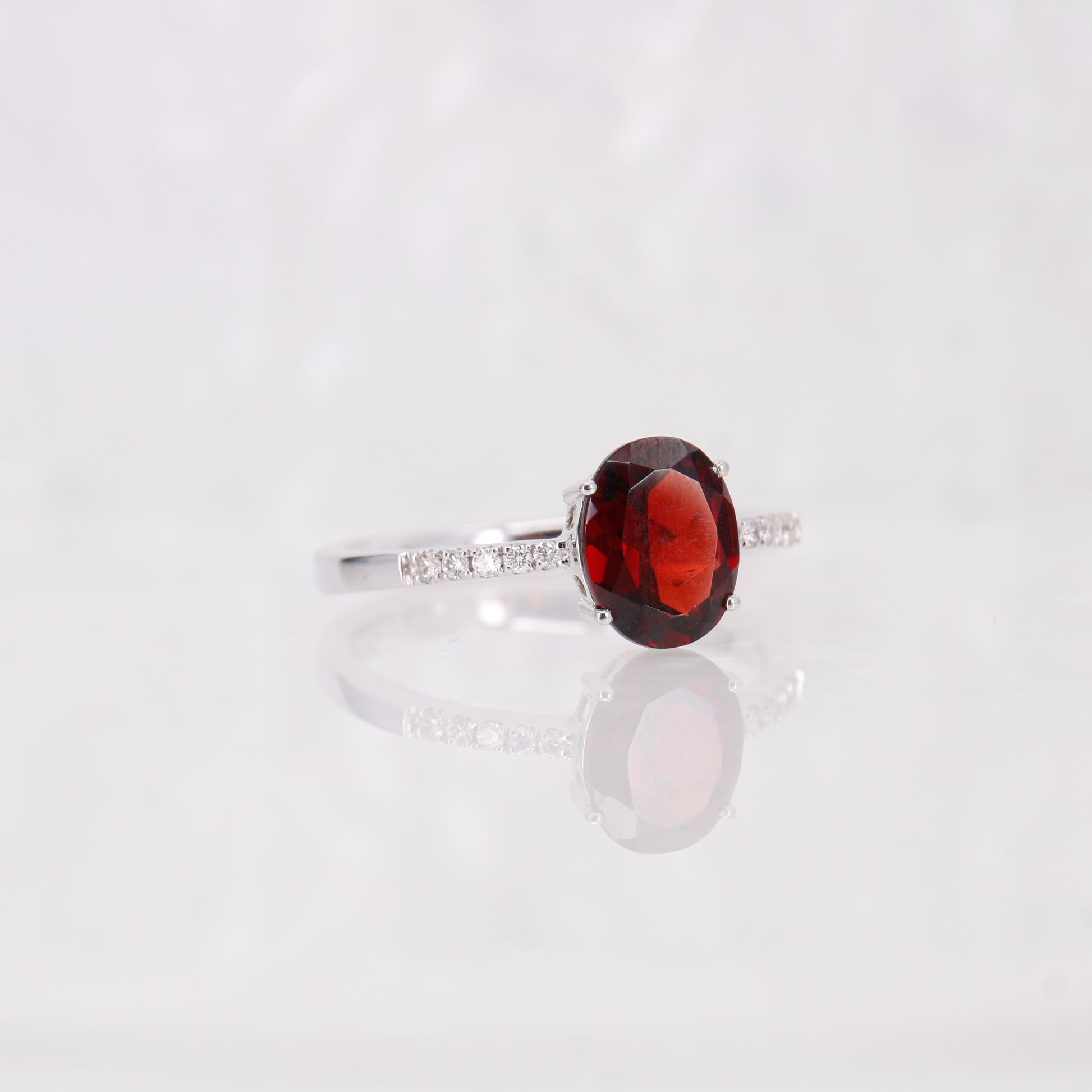 18ct White Gold Garnet and Diamond Engagement Ring. Oval Cut Garnet Ring with diamond shoulders.