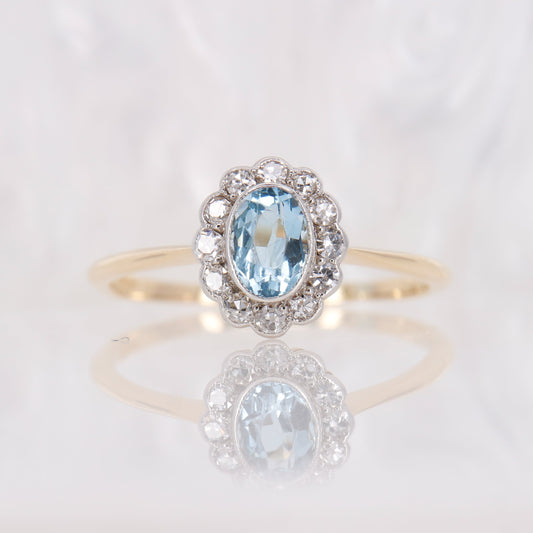 Vintage bezel set oval cut aquamarine and diamond engagement ring. Antique aquamarine and diamond halo iring in 18ct gold.