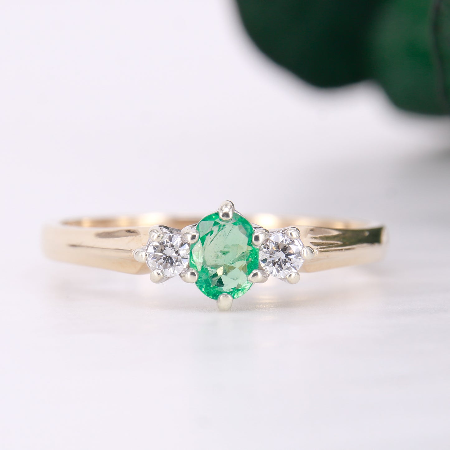 Pre owned oval cut emerald and diamond trilogy three stone ring yellow gold. 