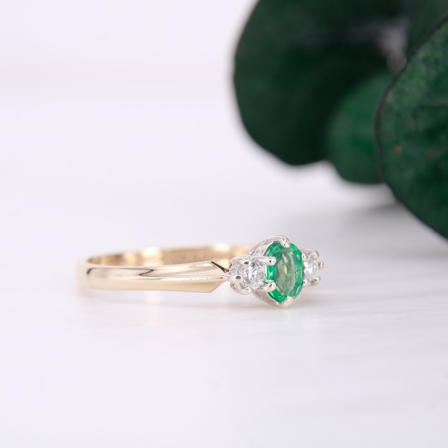 Pre owned oval cut emerald and diamond trilogy three stone ring yellow gold. 