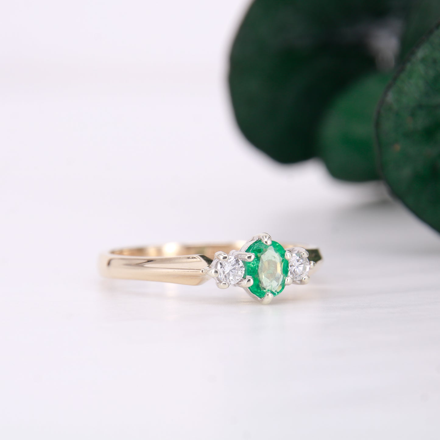 Pre owned oval cut emerald and diamond trilogy three stone ring yellow gold. 